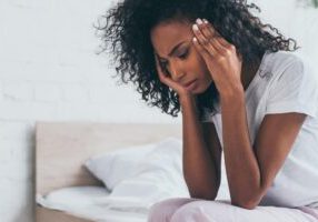 woman-holding-head-while-sitting